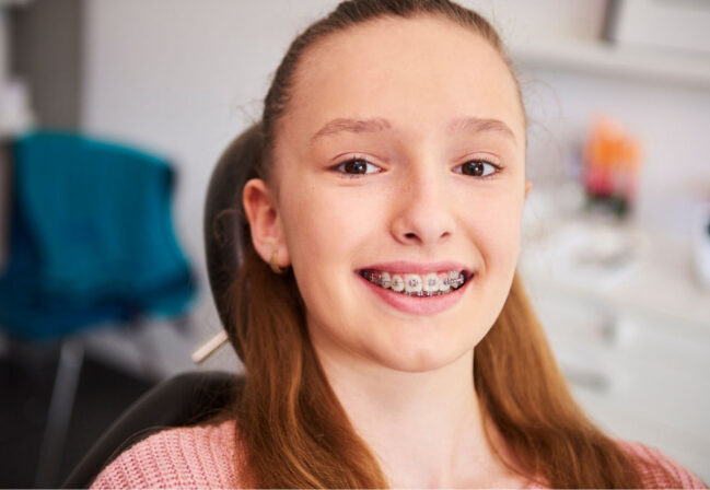 a little girl smile happily with braces